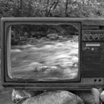 Plateformes de vidéos engagées. Photo en noir et blanc montrant une télévision au bord d'une rivière. dans l'écran, ce qui devrait se trouver à l'arrière de cette télévision.